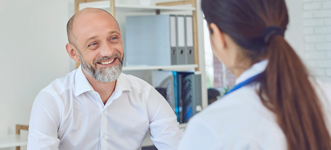 A middle-aged man talks to a doctor in the office. Medical consultation diagnosis prescription in a hospital | Doylestown Health